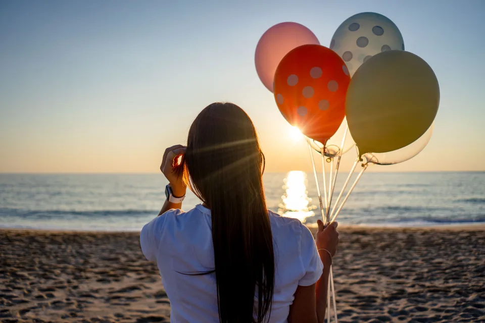 Globos de colores frente al mar al atardecer